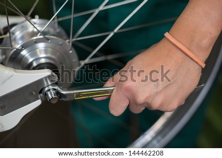 Closeup of bicycle mechanic with a wrench repairing bike wheel