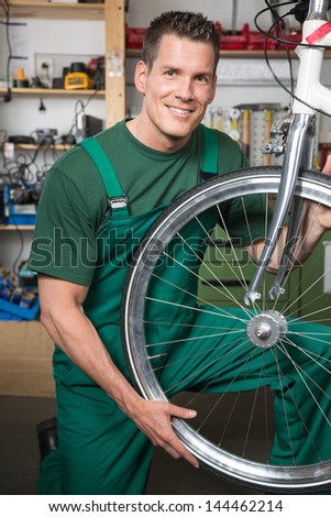 Bicycle mechanic repairing tyre or wheel on bike in a workshop