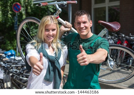 Bicycle mechanic and customer in bike store showing thumbs up
