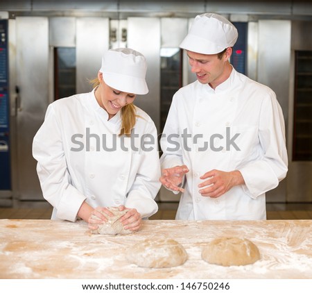 Instructor in bakery teaching baker apprentice how to knead dough