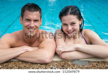 Couple enjoying themselves at public swimming pool smiling
