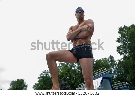 Swimmer posing on starting block at public swimming pool