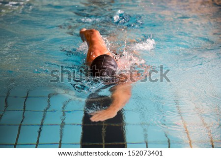 Man swims forward crawl style in public swimming pool