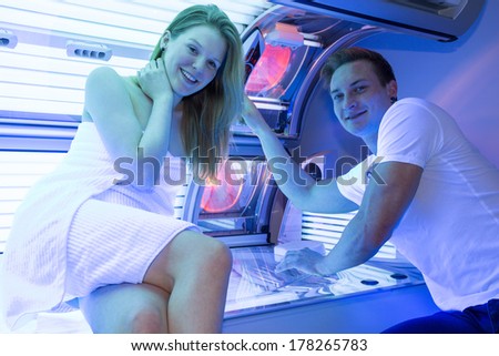 Staff employee in a solarium counseling customer or client at tanning bed