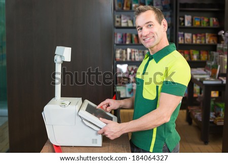 Cashier at cash register in shop or store with books in background
