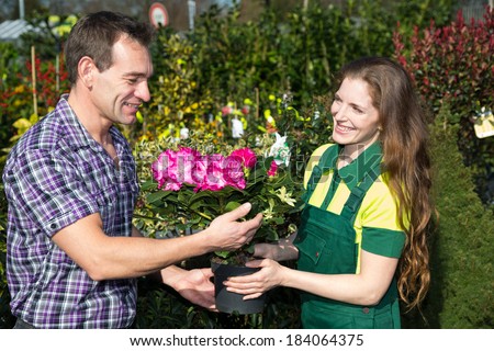 Female florist hands flower to customer in nursery or market garden