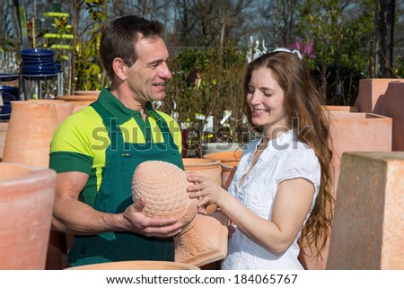 Employee in garden center selling pottery to customer or client