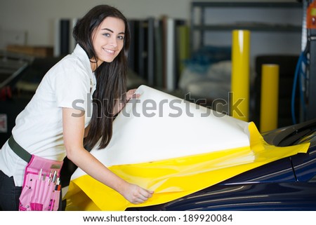 Car wrapper preparing yellow foil to wrap a vehicle