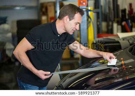 Car wrapper straightening wrapping foil with a squeegee to remove air bubbles