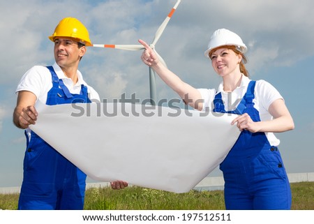 Two engineers with construction plan in wind farm