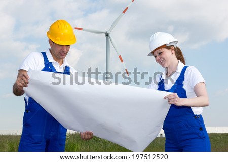 Two engineers with construction plan in wind farm