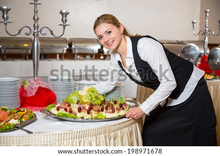Catering service employee or waitress preparing a table for a buffet