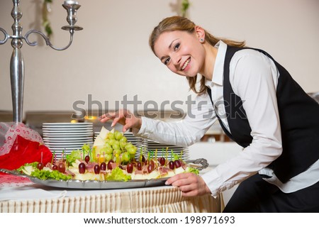 Catering service employee or waitress preparing a table for a buffet