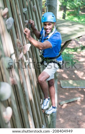 Climber at climbing wall in high rope course