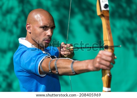 Bowman or archer aiming at target with bow and arrow