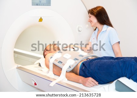Medical technical assistant councelling patient and preparing radiological scan of the torso with magnetic resonance tomography MRI