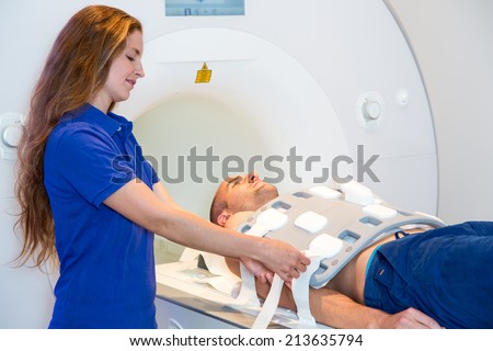 Medical technical assistant councelling patient and preparing radiological scan of the torso with magnetic resonance tomography MRI
