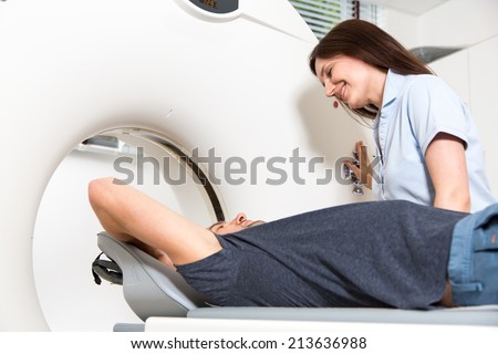 Medical technical assistant councelling patient and preparing scan of the spine with x-ray computed tomography CT  in radiology
