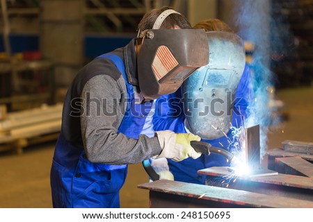 Two steel construction workers welding metal pieces