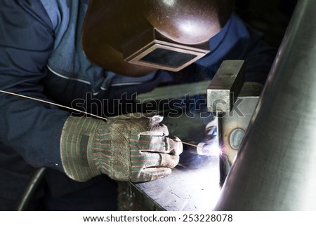 professional welder welding metal parts in steel construction company