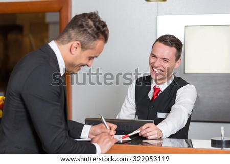 Receptionist at hotel reception assisting a guest