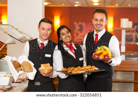 Waitress and waiters posing with food at buffet in restaurant