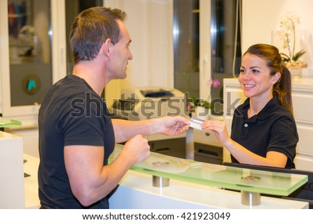 Patient handing an insurance card to doctor\'s receptionist