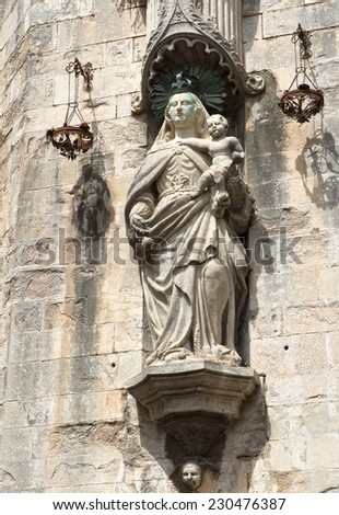 A piece of a facade of a cathedral in Girona, Spain. A woman holding a baby.