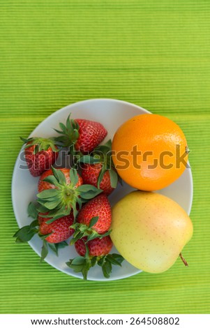 Strawberries, apple and orange on a plate