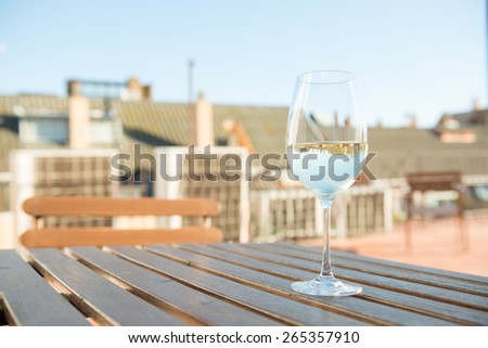 White wine in a glass on an open terrace with the reflection of background houses in wine
