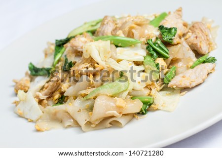 stir fired thin noodles with soy sauce and pork and Kale on white dish