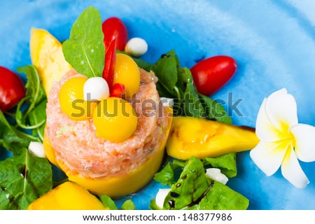 Marinated salmon with yogurt and lemon served with fresh mango,  arugula salad and mozzarella cheese