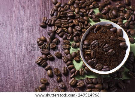 Bowl with coffee beans and ground coffee on a dark photo