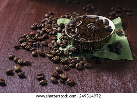 Bowl with coffee beans and ground coffee on a dark photo
