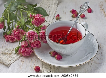 Cup of tea with dried rose buds and fresh roses