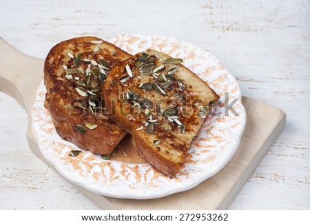 French toast with with pumpkin seeds and honey sauce on a plate