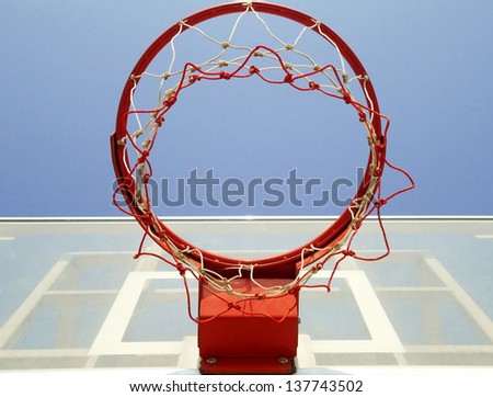 A basketball hoop, net and backboard on a playground, shot from below.