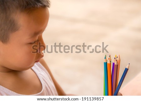 Closeup portrait of a little boy look at colorful pencils