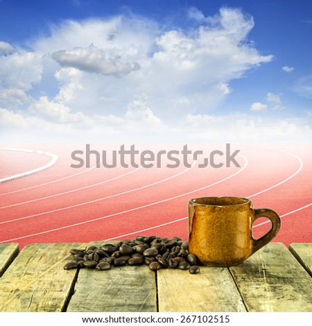 Coffee cup and coffee beans at curve of a running track and blue sky background