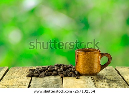 Coffee cup and coffee beans on wooden on green bokeh background