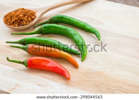 Chili powder and fresh chili on cutting board on wooden table background