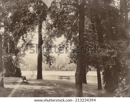 Park near the river - picnic table, trees and river, relaxing nature in sepia retro vintage