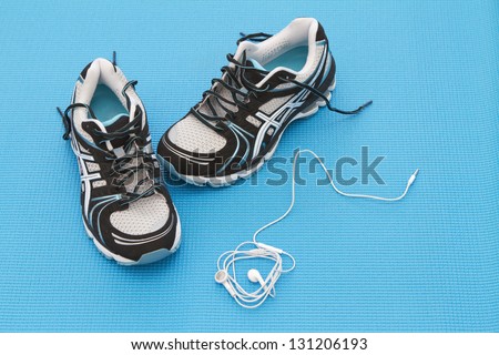 Training shoes and headphones on a blue yoga mat