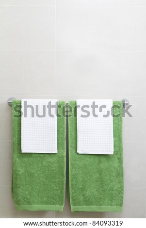 Pair of green and white towels on a rail in a tiled bathroom setting