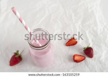 Strawberry milk bottle striped straw on crumpled paper background horizontal