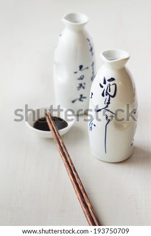 Two white Asian style bottles with soy sauce bowl and chopsticks