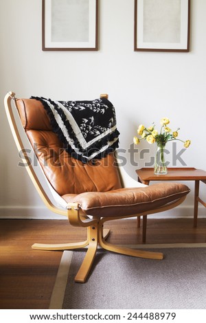 Vintage retro tan leather danish chair and table with vase of flowers