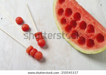 Melon balls on a stick with carved watermelon beside horizontal