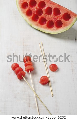 Melon balls on a stick with carved watermelon behind