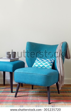 Teal retro armchair and colorful pink pattern rug interior with ottoman
